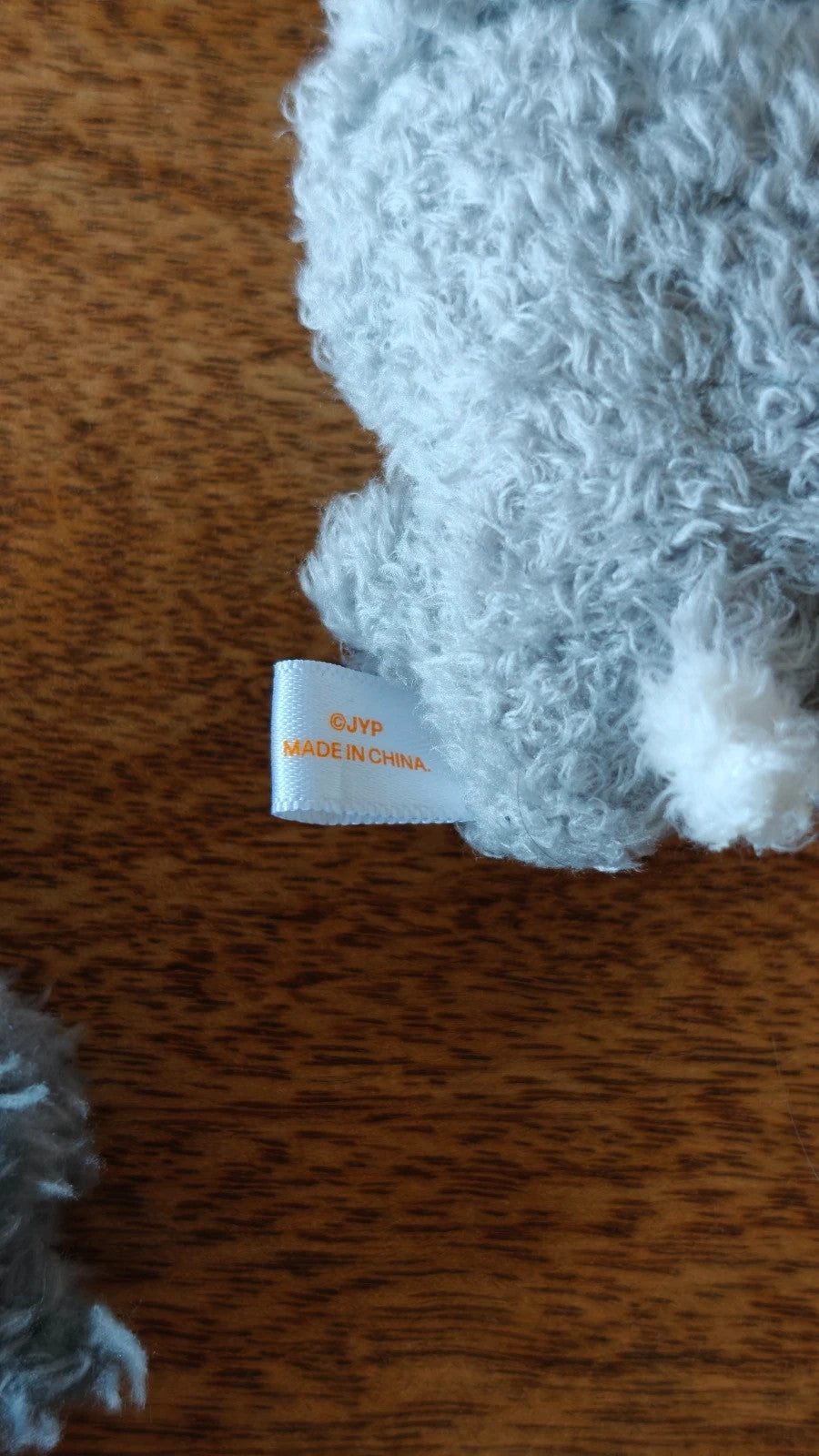 Stray Kids SKZOO Wolf Chan Plush Strap, close-up of the grey plush fabric and label
